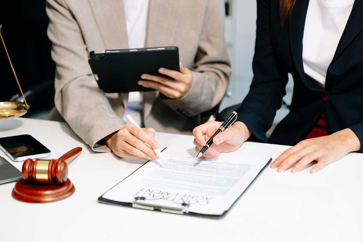 Business and lawyers discussing contract papers with brass scale