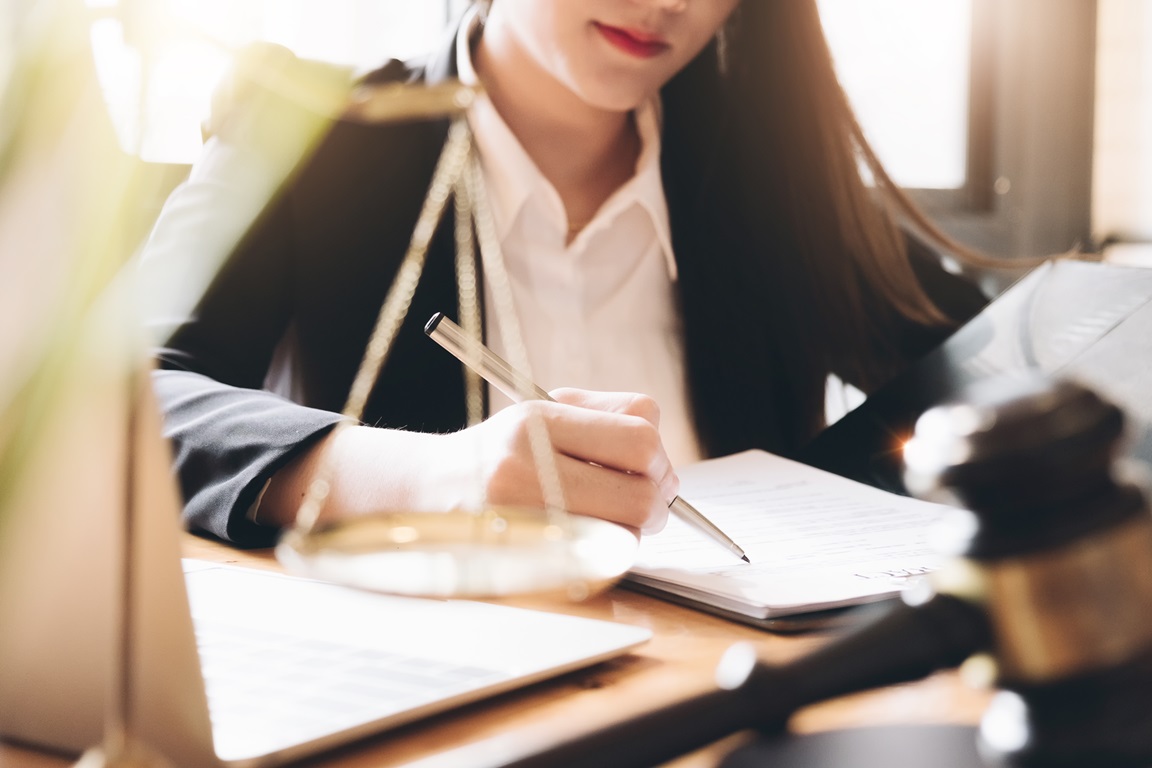Business woman and lawyers discussing contract papers with brass scale on wooden desk in office. Law, legal services, advice, Justice and real estate concept.